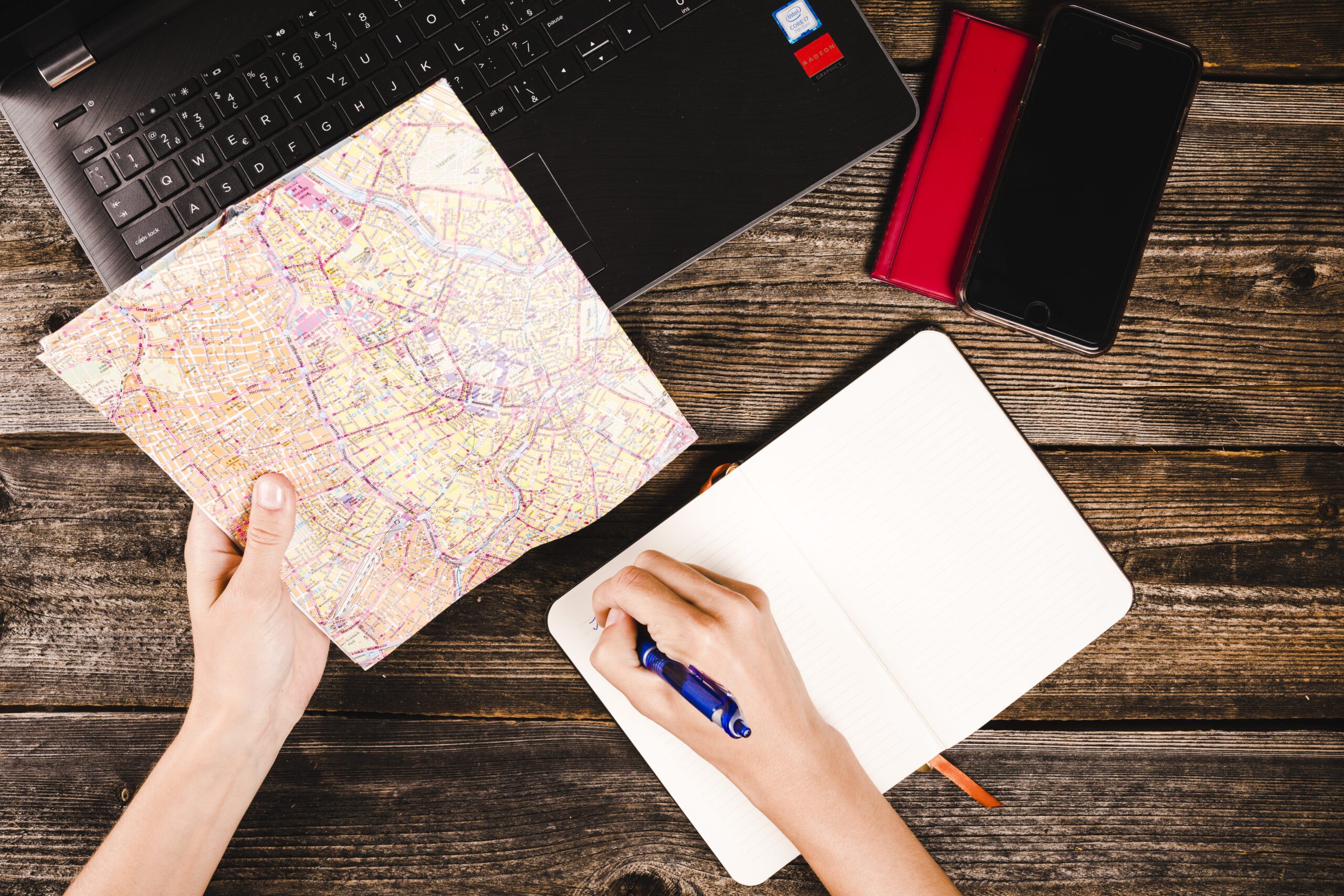 person's hand writing notepad while holding map table