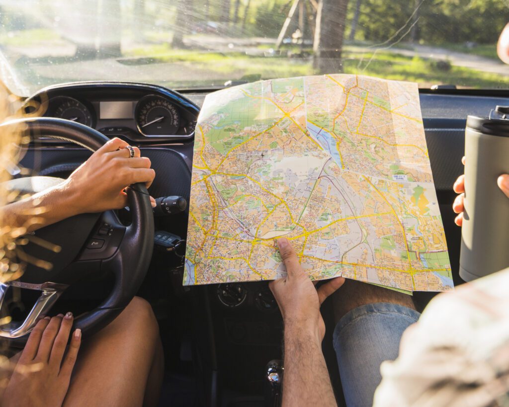 Couple in a car looking into a map choosing a destination for their roadtrip